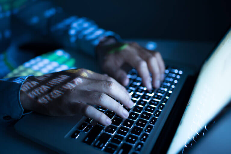 Hands of developer working on computer in the dark